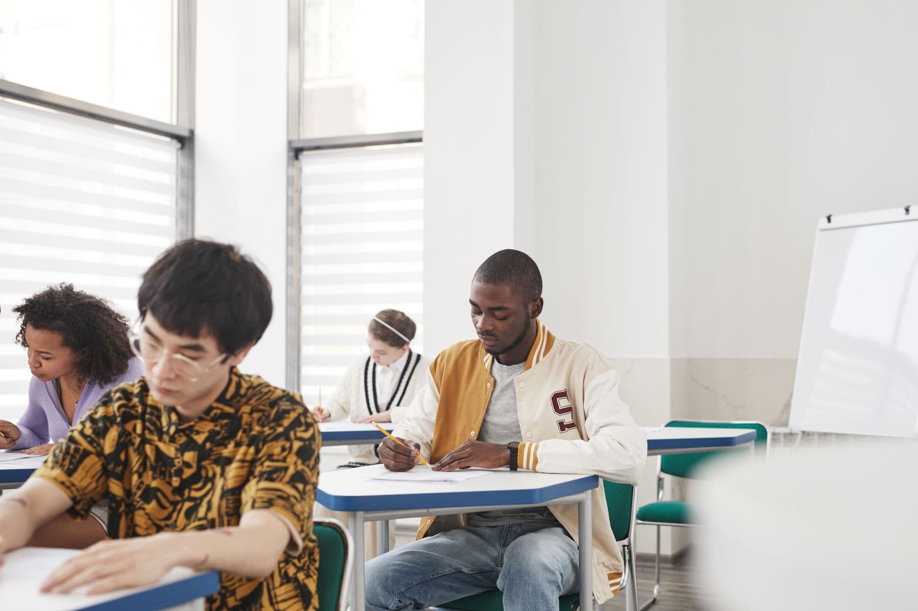 Estudantes fazendo prova em carteiras de sala de aula