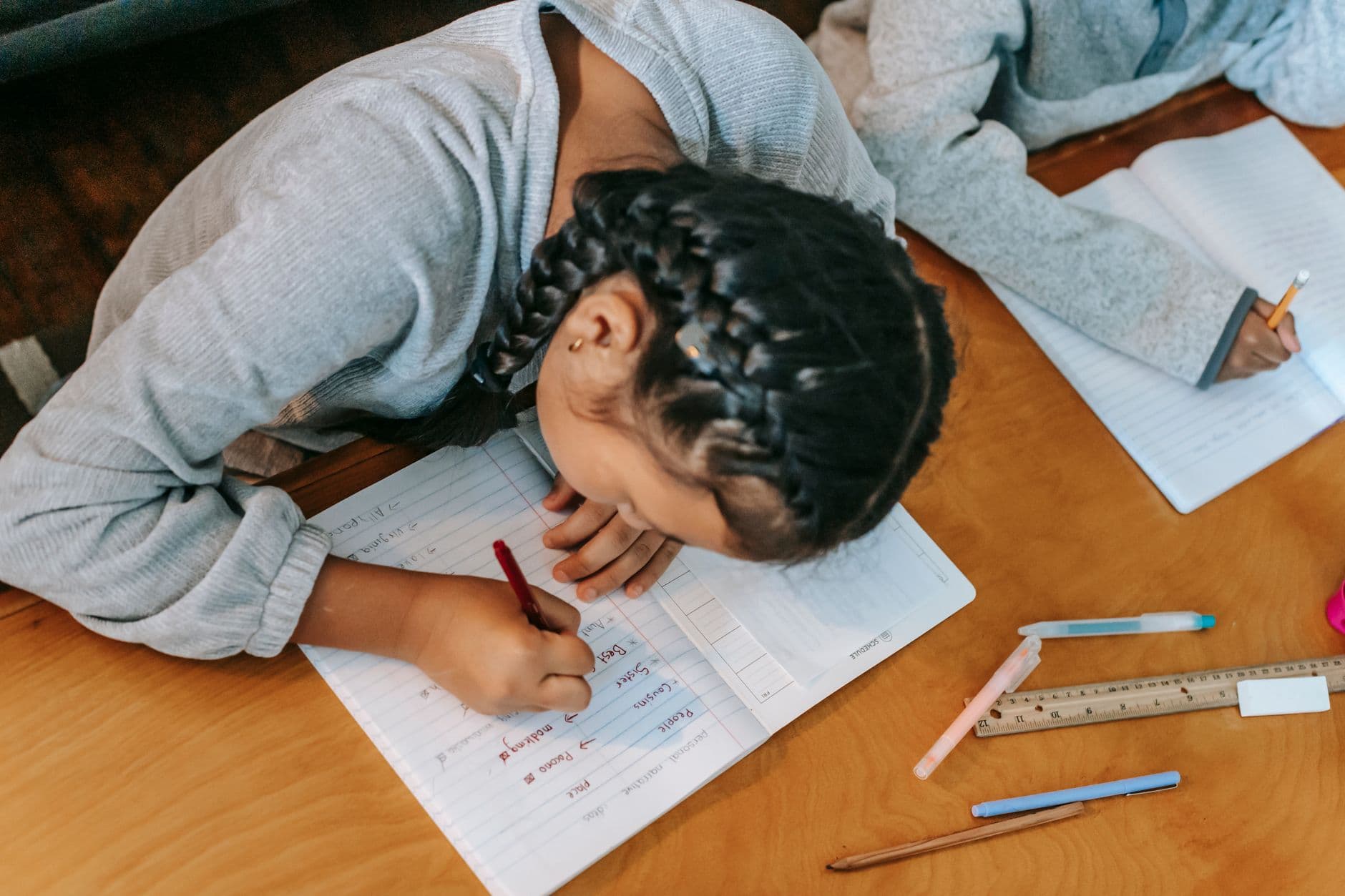Aluna escrevendo palavras de vocabulário em inglês no caderno